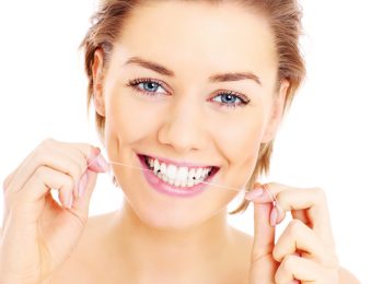 A picture of beautiful womanusing a floss for her teeth over white background
